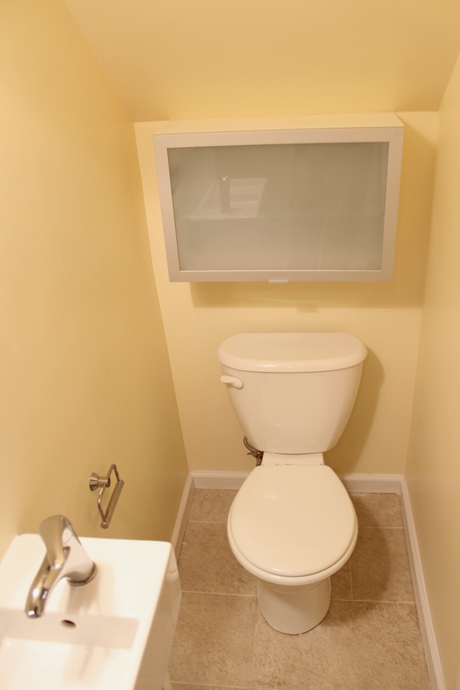 Bild på ett litet funkis badrum, med ett väggmonterat handfat, en hörndusch, en toalettstol med separat cisternkåpa, beige kakel, keramikplattor, gula väggar och klinkergolv i keramik