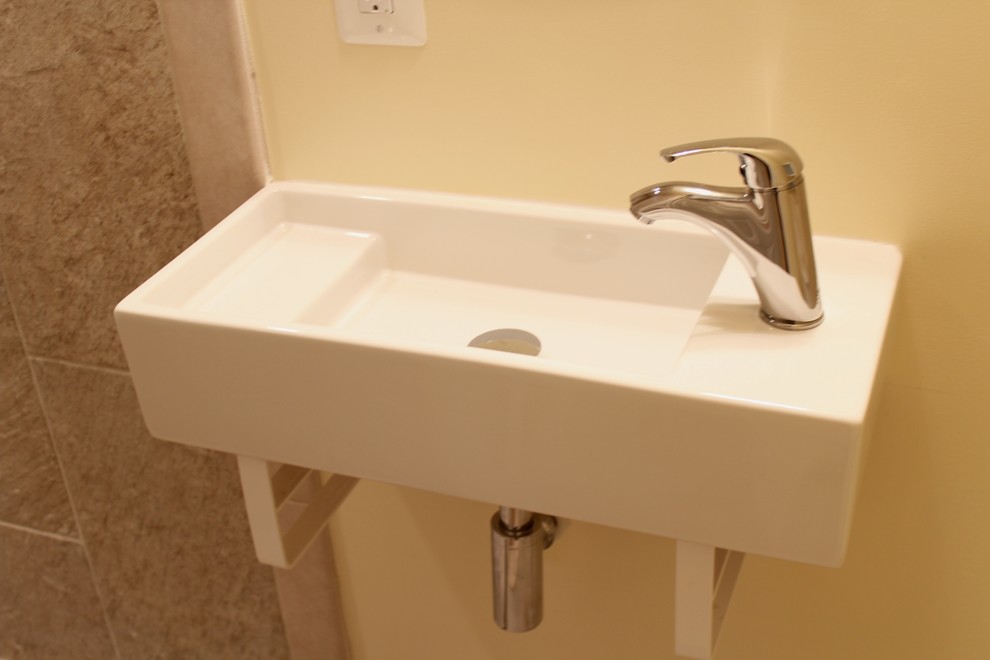 Пример оригинального дизайна: маленькая ванная комната в современном стиле с подвесной раковиной, угловым душем, раздельным унитазом, бежевой плиткой, керамической плиткой, желтыми стенами и полом из керамической плитки для на участке и в саду