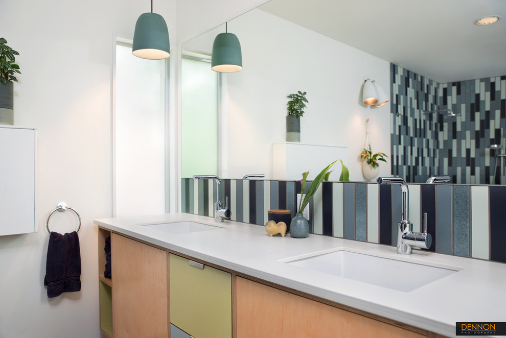 Inspiration for a medium sized retro ensuite bathroom in Seattle with a submerged sink, flat-panel cabinets, light wood cabinets, solid surface worktops, a walk-in shower, a two-piece toilet, blue tiles, ceramic tiles, white walls and porcelain flooring.