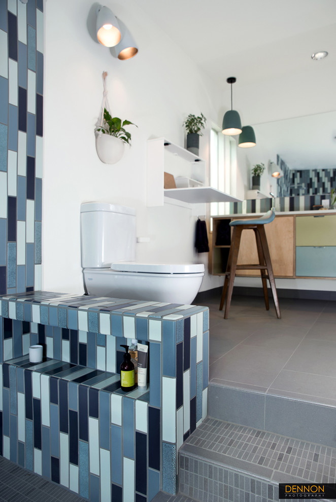 Medium sized retro ensuite bathroom in Seattle with a submerged sink, flat-panel cabinets, light wood cabinets, solid surface worktops, a walk-in shower, a two-piece toilet, blue tiles, ceramic tiles, white walls and porcelain flooring.