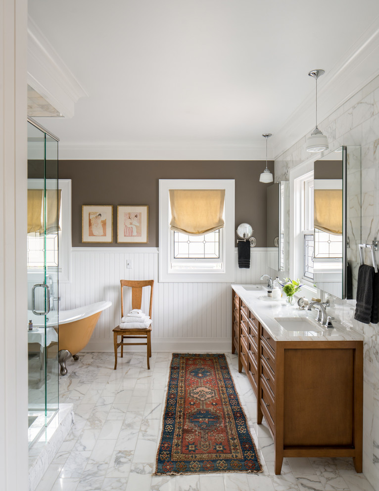 Inspiration pour une salle de bain principale traditionnelle en bois brun avec une baignoire sur pieds, un mur marron, un sol en marbre, un lavabo encastré, un sol blanc, un plan de toilette blanc, une fenêtre et un placard avec porte à panneau encastré.