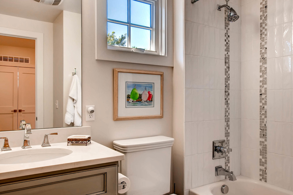 Example of a mid-sized transitional ceramic tile bathroom design in Orange County with recessed-panel cabinets, a two-piece toilet, white walls, an undermount sink and solid surface countertops