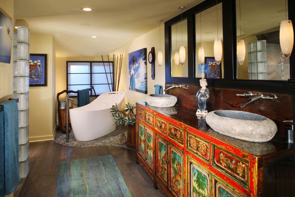 Eclectic master medium tone wood floor freestanding bathtub photo in Denver with furniture-like cabinets and yellow walls