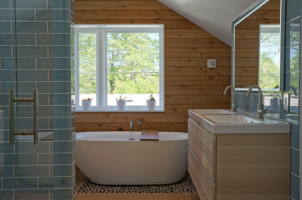 Cette image montre une salle de bain principale marine en bois clair de taille moyenne avec un lavabo intégré, un placard à porte plane, un plan de toilette en surface solide, une baignoire indépendante, une douche ouverte, WC à poser, un carrelage bleu, un carrelage en pâte de verre et un mur blanc.
