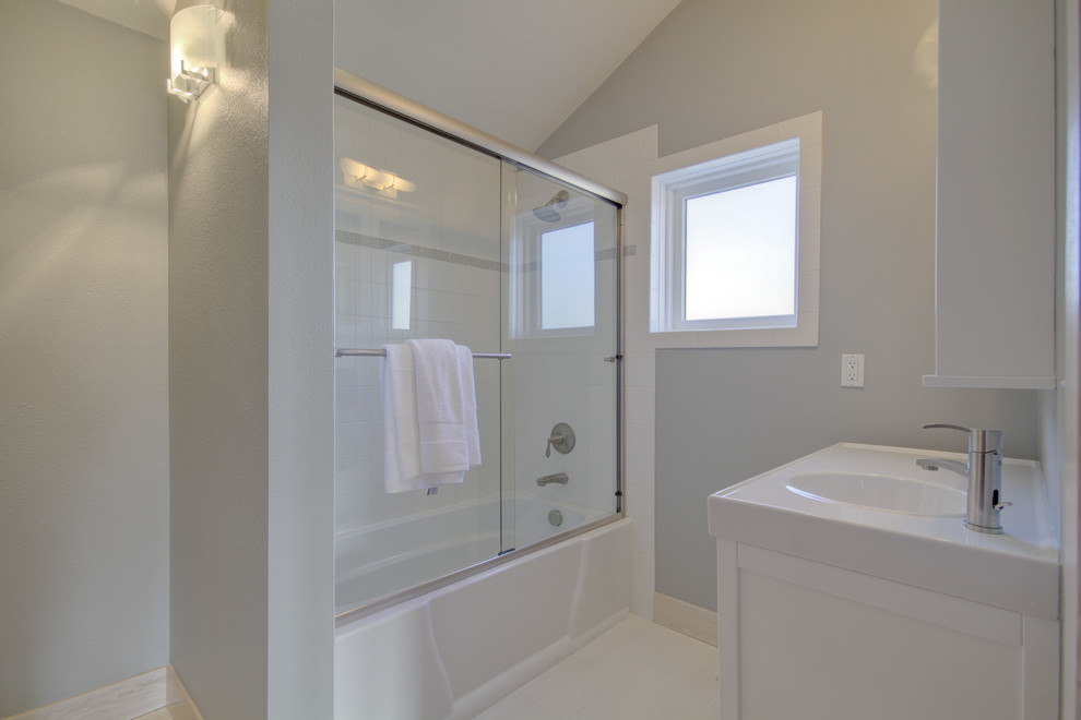 Идея дизайна: ванная комната среднего размера в стиле модернизм с белыми фасадами, душем над ванной, белой плиткой, плиткой кабанчик, серыми стенами, монолитной раковиной, белым полом и душем с раздвижными дверями