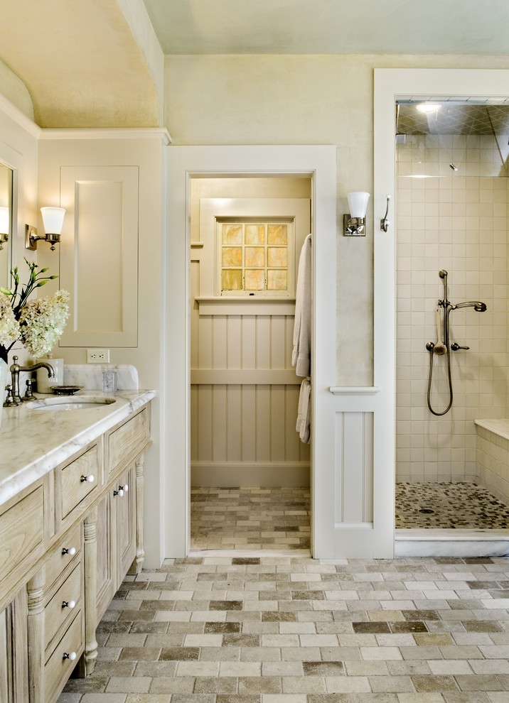 На фото: ванная комната в классическом стиле с врезной раковиной, фасадами с утопленной филенкой, светлыми деревянными фасадами, душем в нише, бежевой плиткой, каменной плиткой и бежевым полом
