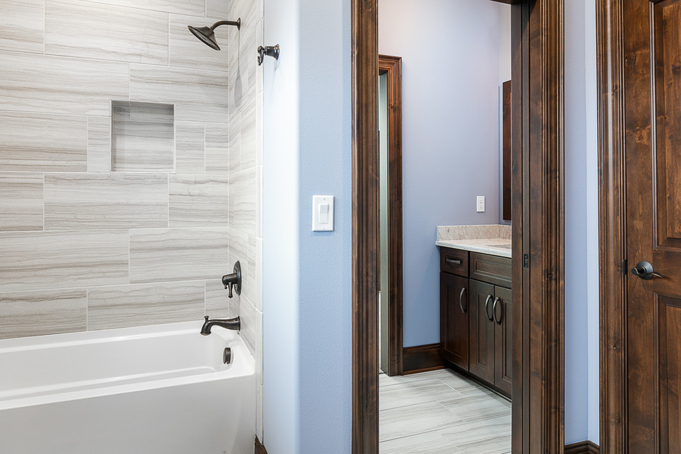 Inredning av ett amerikanskt stort grå grått badrum med dusch, med luckor med infälld panel, skåp i mörkt trä, ett badkar i en alkov, en dusch/badkar-kombination, blå väggar, klinkergolv i porslin, ett undermonterad handfat, granitbänkskiva, beiget golv och dusch med duschdraperi