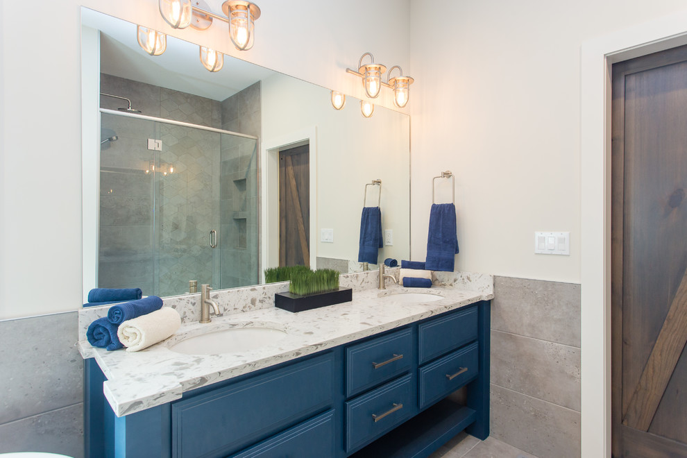 Inspiration for a large urban ensuite bathroom in Calgary with flat-panel cabinets, blue cabinets, a freestanding bath, a built-in shower, a one-piece toilet, white walls, ceramic flooring, a submerged sink and engineered stone worktops.