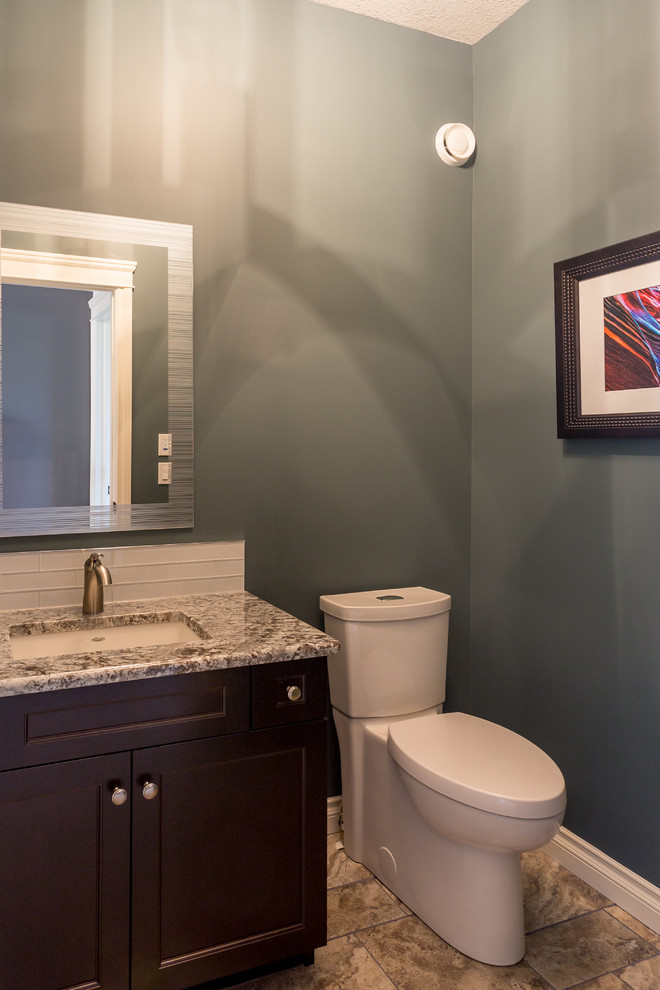 Immagine di una piccola stanza da bagno con doccia classica con lavabo sottopiano, ante in stile shaker, ante in legno bruno, top in granito, WC monopezzo, piastrelle bianche, piastrelle di vetro, pareti blu e pavimento con piastrelle in ceramica