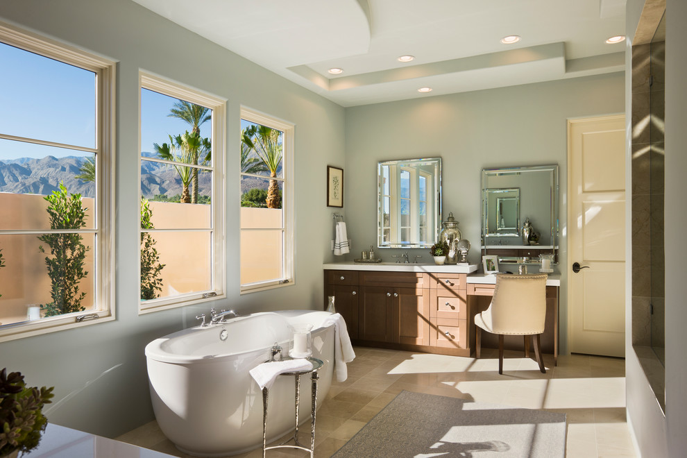 Design ideas for a medium sized traditional ensuite bathroom in Orange County with shaker cabinets, medium wood cabinets, a freestanding bath, green walls, ceramic flooring, solid surface worktops and beige floors.
