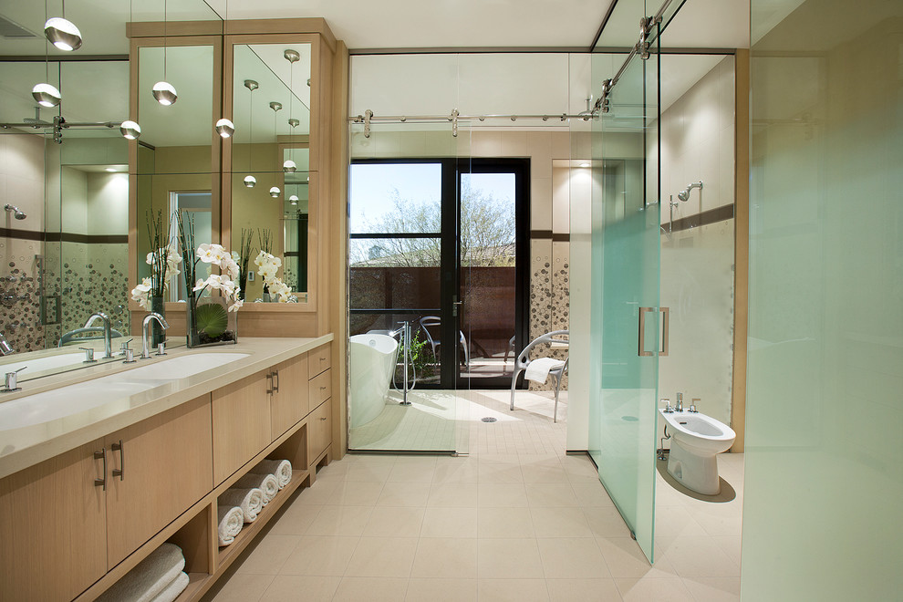 Свежая идея для дизайна: ванная комната в современном стиле с раковиной с несколькими смесителями, плоскими фасадами, светлыми деревянными фасадами, отдельно стоящей ванной и биде - отличное фото интерьера