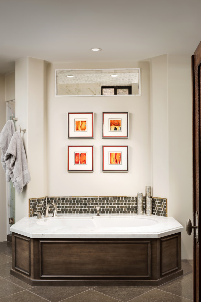 Bild på ett mellanstort amerikanskt en-suite badrum, med luckor med infälld panel, skåp i mellenmörkt trä, ett undermonterat badkar, en dusch i en alkov, en toalettstol med hel cisternkåpa, flerfärgad kakel, stenkakel, kalkstensgolv, ett undermonterad handfat, marmorbänkskiva och beige väggar
