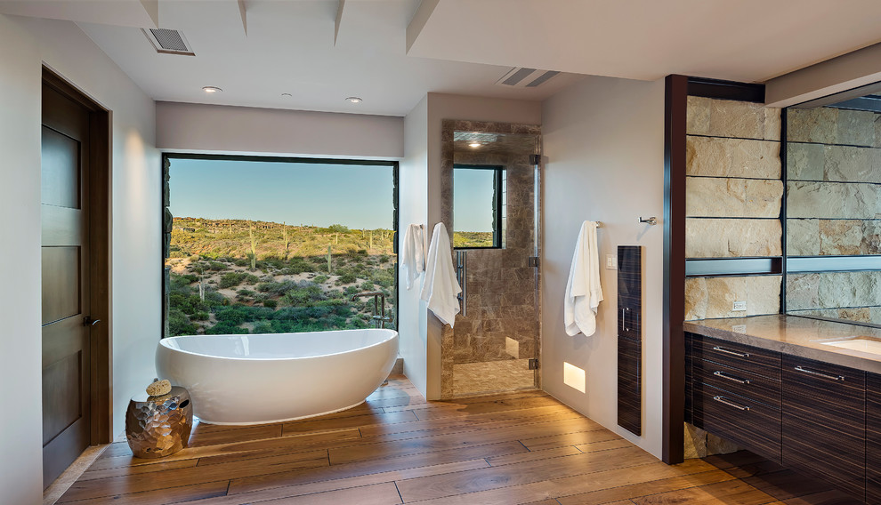 Foto di una grande stanza da bagno padronale stile americano con vasca freestanding, piastrelle in pietra, parquet chiaro e porta doccia a battente
