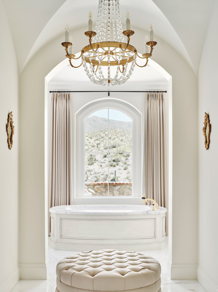Medelhavsstil inredning av ett badrum, med ett fristående badkar och marmorgolv