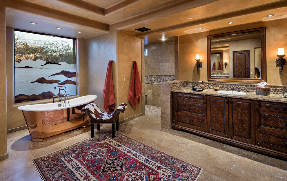 Idéer för amerikanska en-suite badrum, med möbel-liknande, skåp i slitet trä, ett fristående badkar, en dusch i en alkov, en toalettstol med hel cisternkåpa, kakel i småsten, bruna väggar, travertin golv, ett nedsänkt handfat, granitbänkskiva och med dusch som är öppen