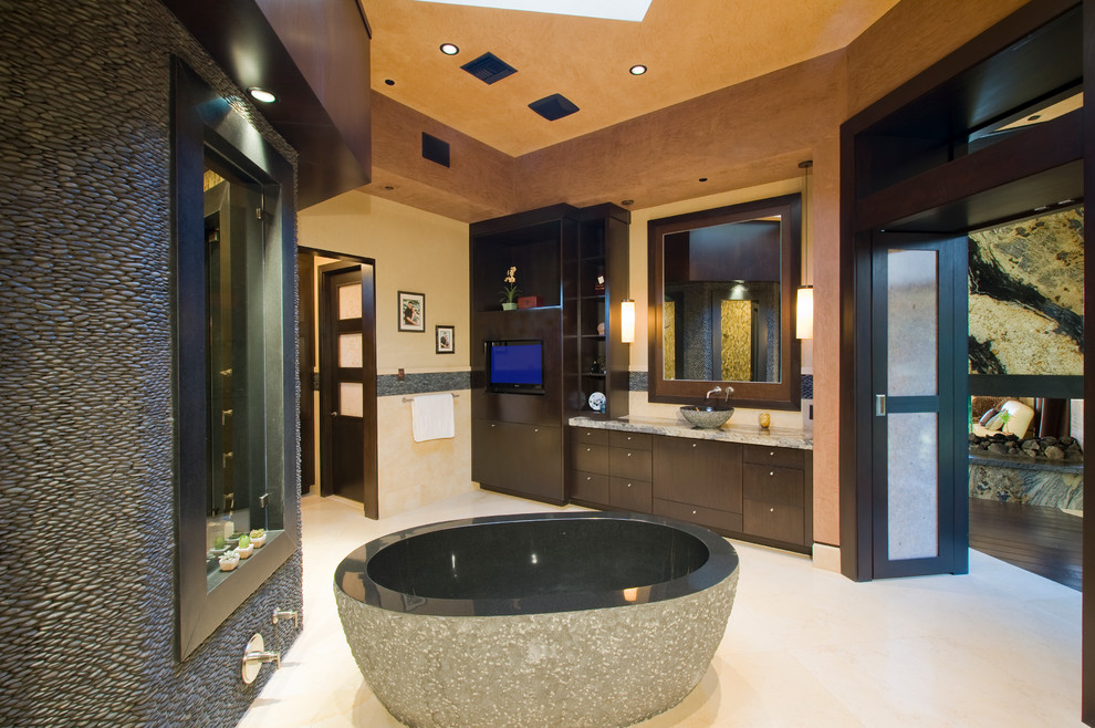 Modernes Badezimmer mit Aufsatzwaschbecken, freistehender Badewanne und Steinwänden in Las Vegas