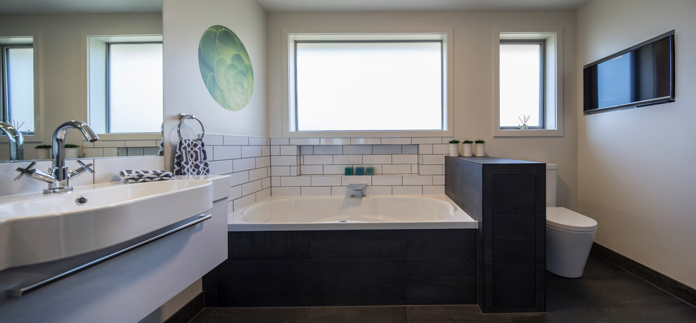 Medium sized contemporary ensuite bathroom in Dunedin with white cabinets, a built-in bath, an alcove shower, a one-piece toilet, white tiles, metro tiles, white walls, porcelain flooring, an integrated sink and solid surface worktops.