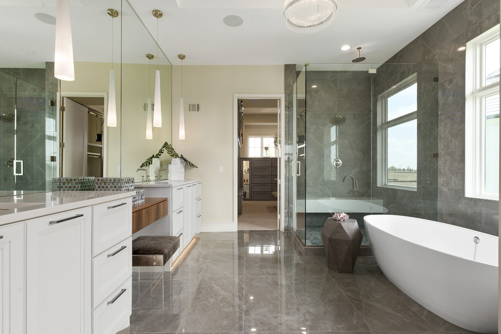 На фото: главная ванная комната среднего размера в современном стиле с белыми фасадами, отдельно стоящей ванной, угловым душем, серой плиткой, врезной раковиной, серым полом, душем с распашными дверями и белой столешницей