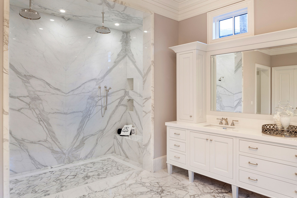 Cette image montre une douche en alcôve minimaliste avec un placard à porte shaker, des portes de placard blanches, une baignoire indépendante, des dalles de pierre, un mur beige, un sol en marbre, un lavabo encastré, un plan de toilette en quartz et une cabine de douche à porte battante.
