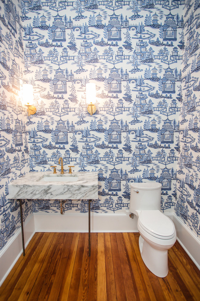 Asiatisk inredning av ett litet vit vitt toalett, med en toalettstol med separat cisternkåpa, blå väggar, mellanmörkt trägolv, ett konsol handfat, marmorbänkskiva och brunt golv