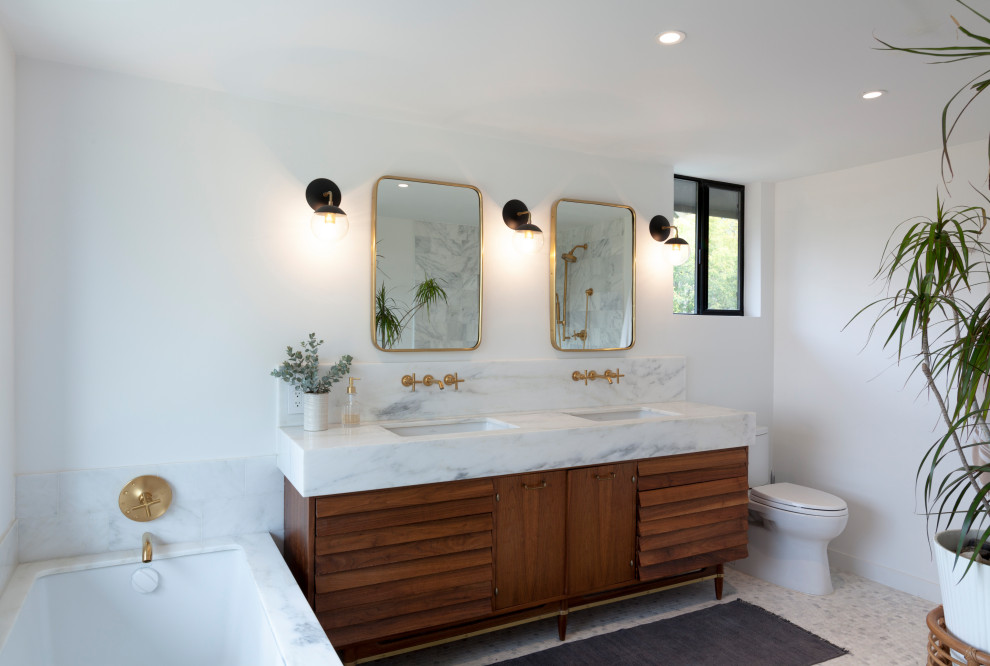 Modernes Badezimmer mit Lamellenschränken, hellbraunen Holzschränken, Unterbauwanne, weißer Wandfarbe, Unterbauwaschbecken, grauem Boden, weißer Waschtischplatte, Doppelwaschbecken und freistehendem Waschtisch in Los Angeles