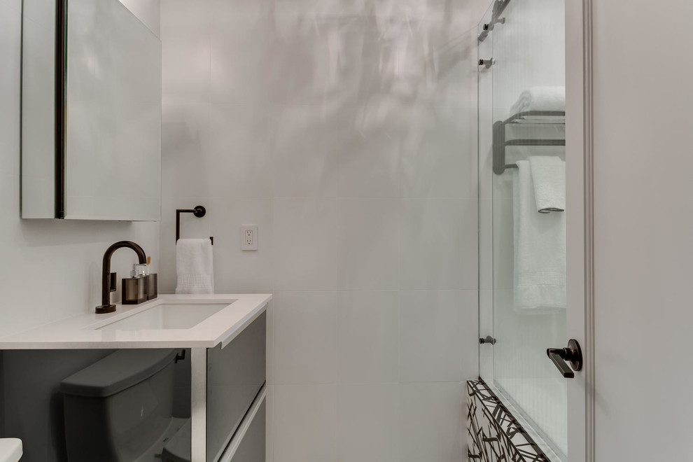 Idée de décoration pour une salle d'eau design de taille moyenne avec un placard en trompe-l'oeil, une baignoire en alcôve, un combiné douche/baignoire, WC à poser, un carrelage blanc, des carreaux de céramique, un mur blanc, un sol en carrelage de céramique, un lavabo encastré, un plan de toilette en surface solide, un sol multicolore, une cabine de douche à porte coulissante et un plan de toilette blanc.