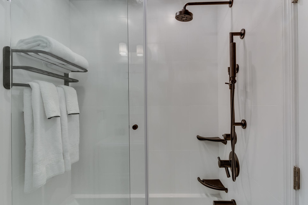 На фото: ванная комната среднего размера в современном стиле с белыми стенами, душем с раздвижными дверями, фасадами островного типа, ванной в нише, душем над ванной, унитазом-моноблоком, белой плиткой, керамической плиткой, полом из керамической плитки, врезной раковиной, столешницей из искусственного камня, разноцветным полом, душевой кабиной и белой столешницей