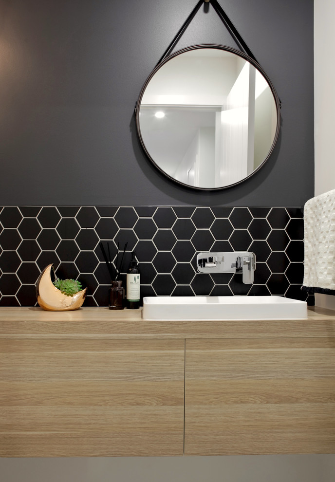 На фото: маленькая ванная комната в стиле модернизм с светлыми деревянными фасадами, черной плиткой, керамической плиткой, черными стенами, полом из керамической плитки, накладной раковиной и столешницей из ламината для на участке и в саду