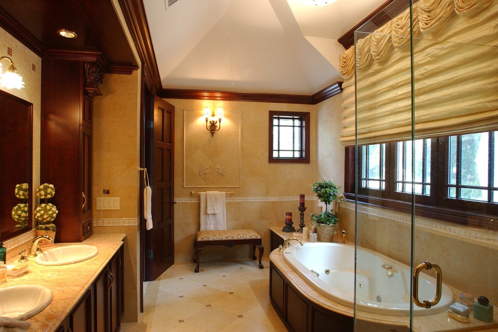 Esempio di una grande stanza da bagno padronale classica con ante con riquadro incassato, ante in legno bruno, vasca da incasso, doccia alcova, piastrelle beige, pareti beige, lavabo sottopiano e top in marmo