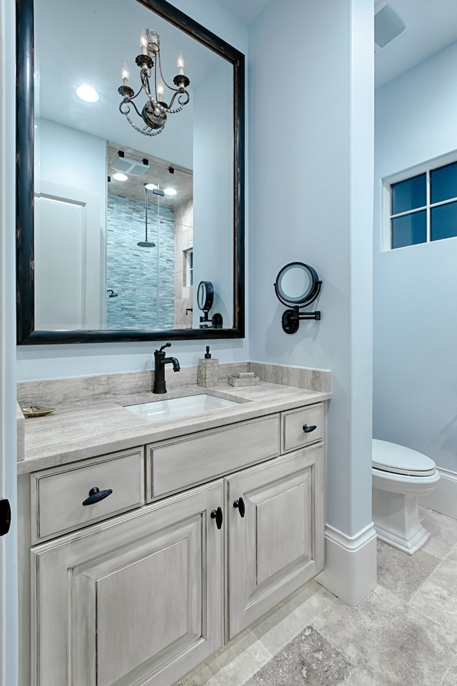 Cette image montre une salle de bain traditionnelle de taille moyenne avec un placard avec porte à panneau surélevé, des portes de placard beiges, une baignoire en alcôve, WC séparés, un carrelage beige, des carreaux de porcelaine, un mur bleu, un sol en carrelage de porcelaine, un lavabo encastré, un plan de toilette en granite, un sol beige et une cabine de douche à porte battante.