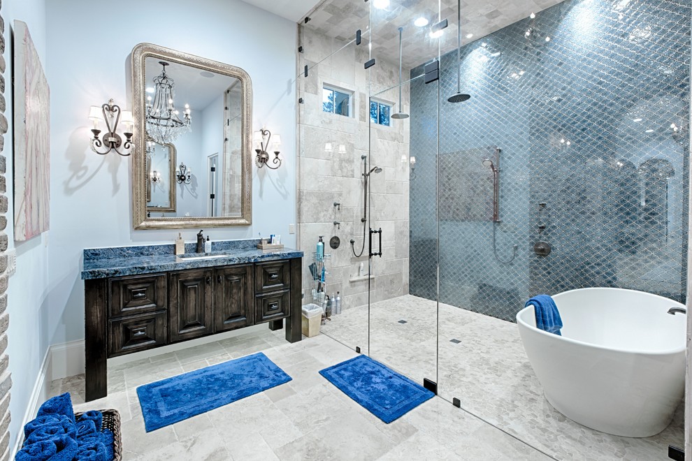 Стильный дизайн: главная ванная комната среднего размера в средиземноморском стиле с фасадами с выступающей филенкой, коричневыми фасадами, отдельно стоящей ванной, душевой комнатой, бежевой плиткой, синей плиткой, керамогранитной плиткой, синими стенами, полом из керамогранита, врезной раковиной, столешницей из гранита, бежевым полом и душем с распашными дверями - последний тренд