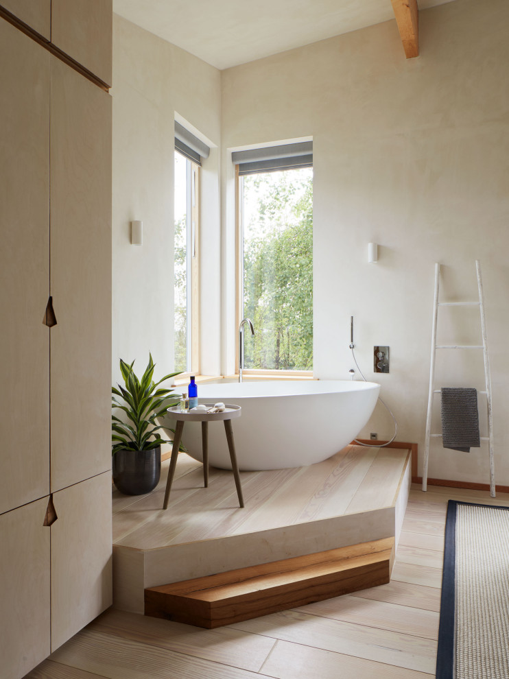 На фото: главная ванная комната в современном стиле с отдельно стоящей ванной, светлым паркетным полом и бежевым полом