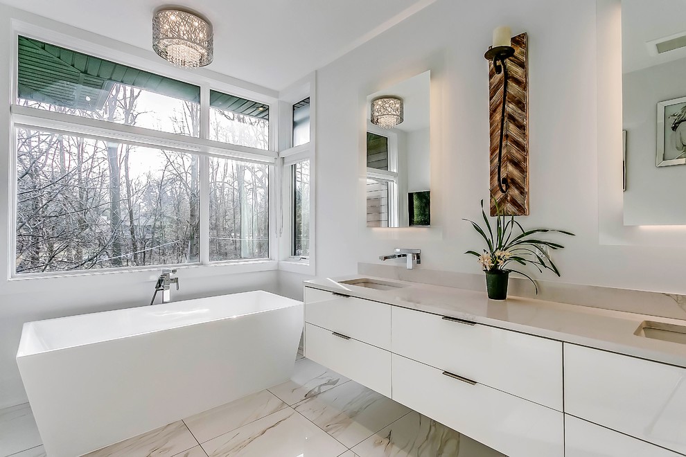 Idéer för funkis en-suite badrum, med släta luckor, vita skåp, ett fristående badkar, vita väggar, marmorgolv, ett undermonterad handfat, bänkskiva i kvarts och vitt golv