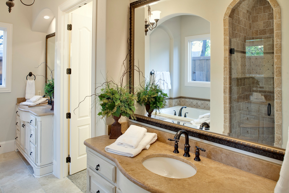 Inspiration pour une salle de bain principale traditionnelle de taille moyenne avec un placard avec porte à panneau surélevé, des portes de placard blanches, une baignoire posée, une douche d'angle, un carrelage beige, un carrelage de pierre, un mur beige, un sol en carrelage de céramique et un lavabo encastré.