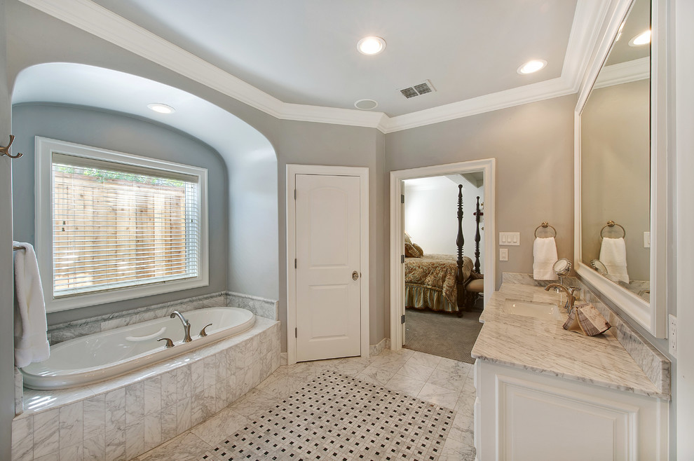 Klassisk inredning av ett stort en-suite badrum, med luckor med infälld panel, vita skåp, ett platsbyggt badkar, en dusch i en alkov, grå kakel, vit kakel, stenkakel, grå väggar, marmorgolv, ett undermonterad handfat och marmorbänkskiva