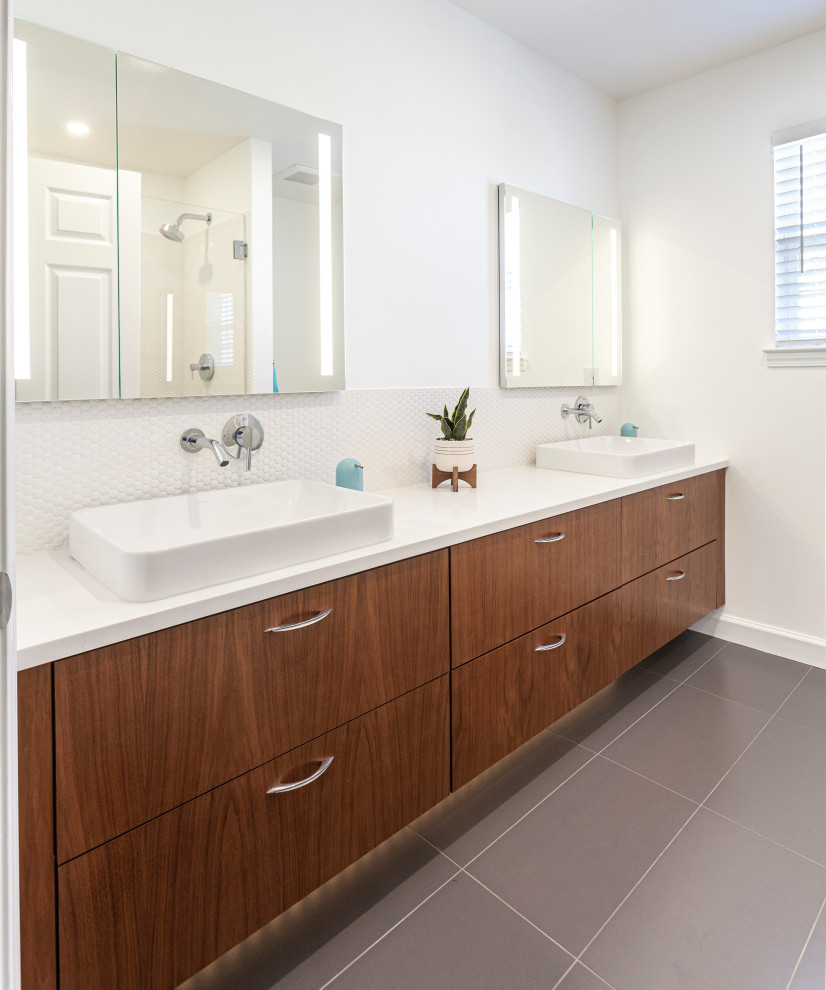 Photo of a medium sized midcentury ensuite bathroom in Detroit with flat-panel cabinets, brown cabinets, a walk-in shower, a one-piece toilet, white tiles, white walls, ceramic flooring, a vessel sink, engineered stone worktops, grey floors, a hinged door, white worktops, double sinks and a floating vanity unit.