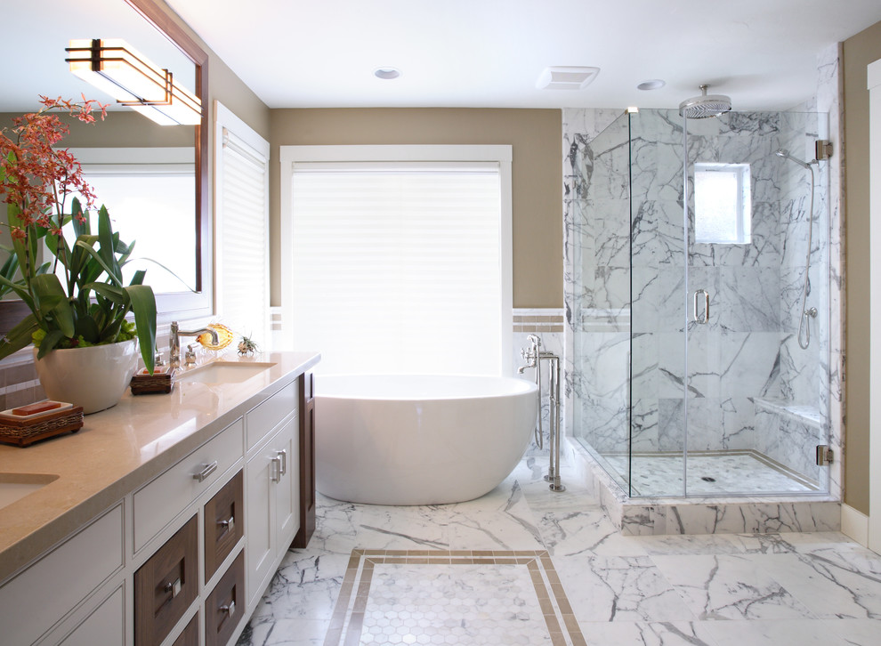 Exemple d'une salle de bain principale chic de taille moyenne avec des portes de placard blanches, une baignoire indépendante, une douche d'angle, un mur beige, un sol en marbre, un placard à porte shaker, un lavabo encastré et un plan de toilette en surface solide.