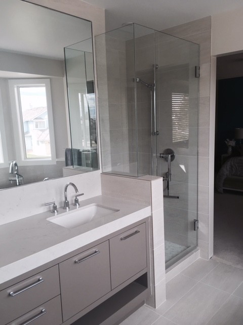 Inspiration for a medium sized contemporary ensuite bathroom in Calgary with flat-panel cabinets, beige cabinets, a freestanding bath, a corner shower, a two-piece toilet, beige tiles, porcelain tiles, beige walls, porcelain flooring, a submerged sink, engineered stone worktops, beige floors and a hinged door.
