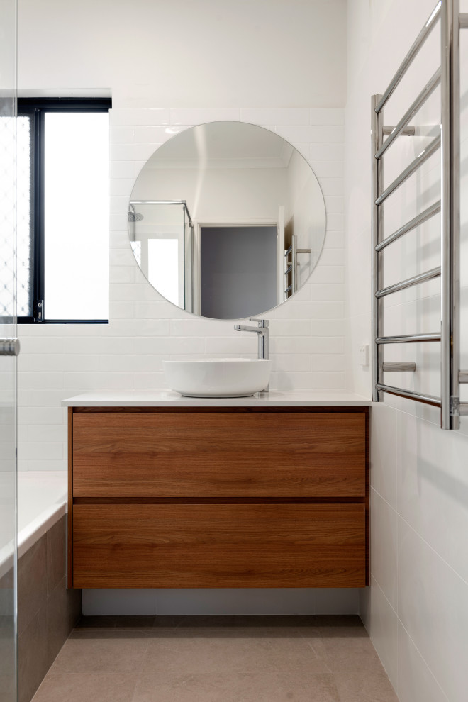 Идея дизайна: ванная комната среднего размера в стиле модернизм с фасадами цвета дерева среднего тона, угловой ванной, угловым душем, белой плиткой, керамической плиткой, белыми стенами, полом из керамической плитки, настольной раковиной, бежевым полом, душем с распашными дверями и белой столешницей
