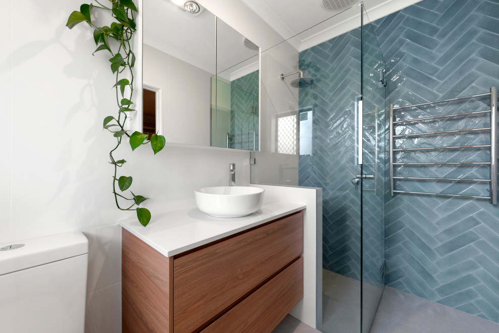 Пример оригинального дизайна: главная ванная комната среднего размера в современном стиле с фасадами цвета дерева среднего тона, угловой ванной, угловым душем, унитазом-моноблоком, синей плиткой, керамической плиткой, белыми стенами, полом из керамической плитки, настольной раковиной, бежевым полом, душем с распашными дверями и белой столешницей