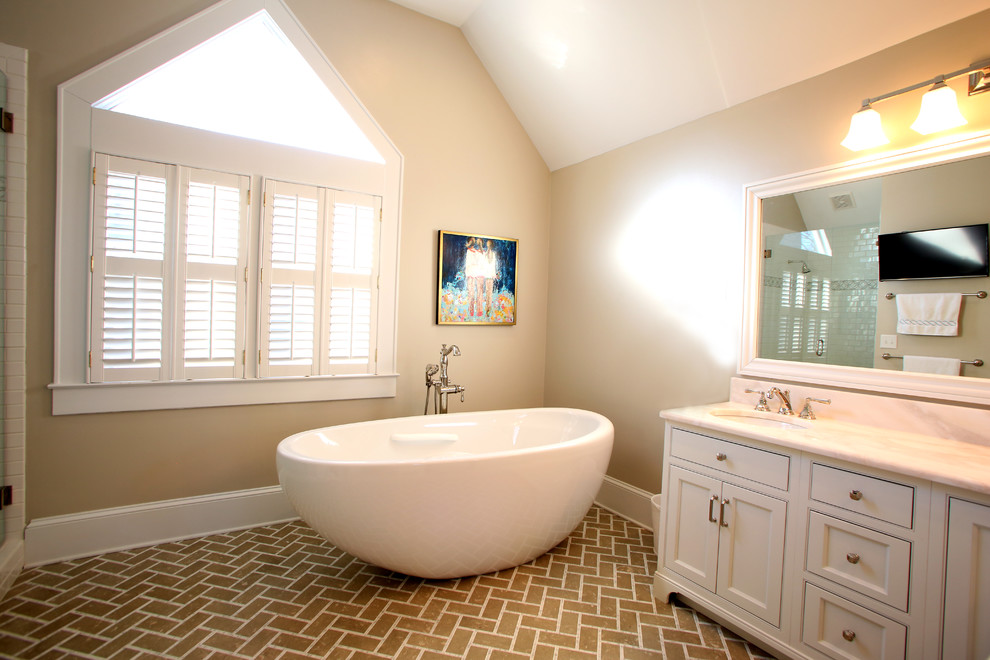 Esempio di una stanza da bagno padronale tradizionale di medie dimensioni con ante con riquadro incassato, ante bianche, vasca freestanding, pavimento in marmo, lavabo sottopiano, top in marmo e pavimento beige
