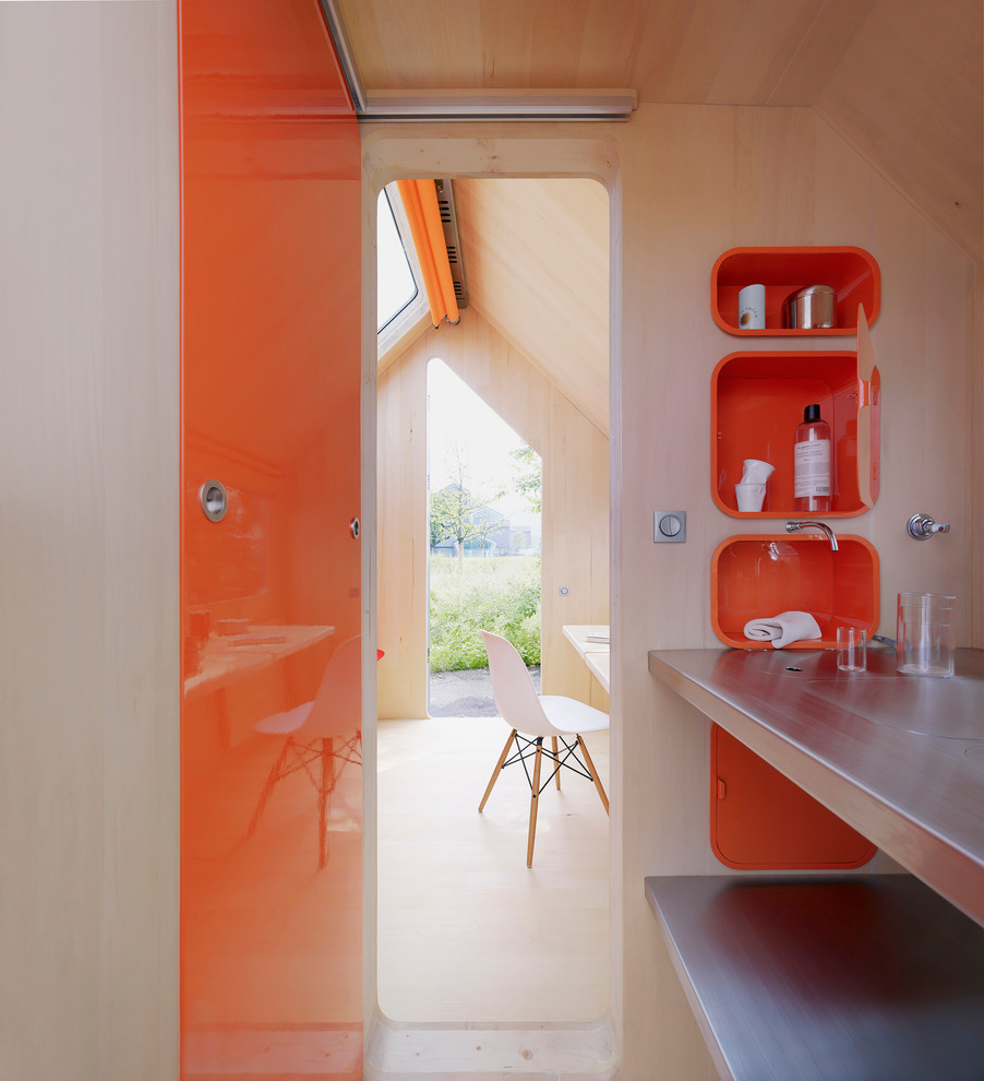 Inspiration pour une salle de bain minimaliste avec un placard sans porte, des portes de placard oranges et un plan de toilette en acier inoxydable.