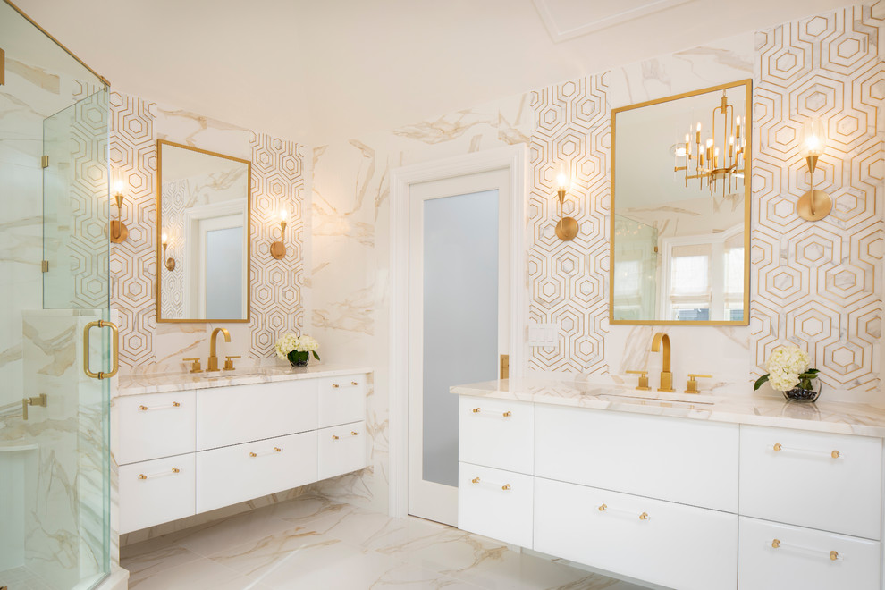 Inredning av ett modernt stort vit vitt en-suite badrum, med släta luckor, vita skåp, ett fristående badkar, en hörndusch, en toalettstol med hel cisternkåpa, vit kakel, marmorkakel, vita väggar, marmorgolv, ett undermonterad handfat, marmorbänkskiva, vitt golv och dusch med gångjärnsdörr