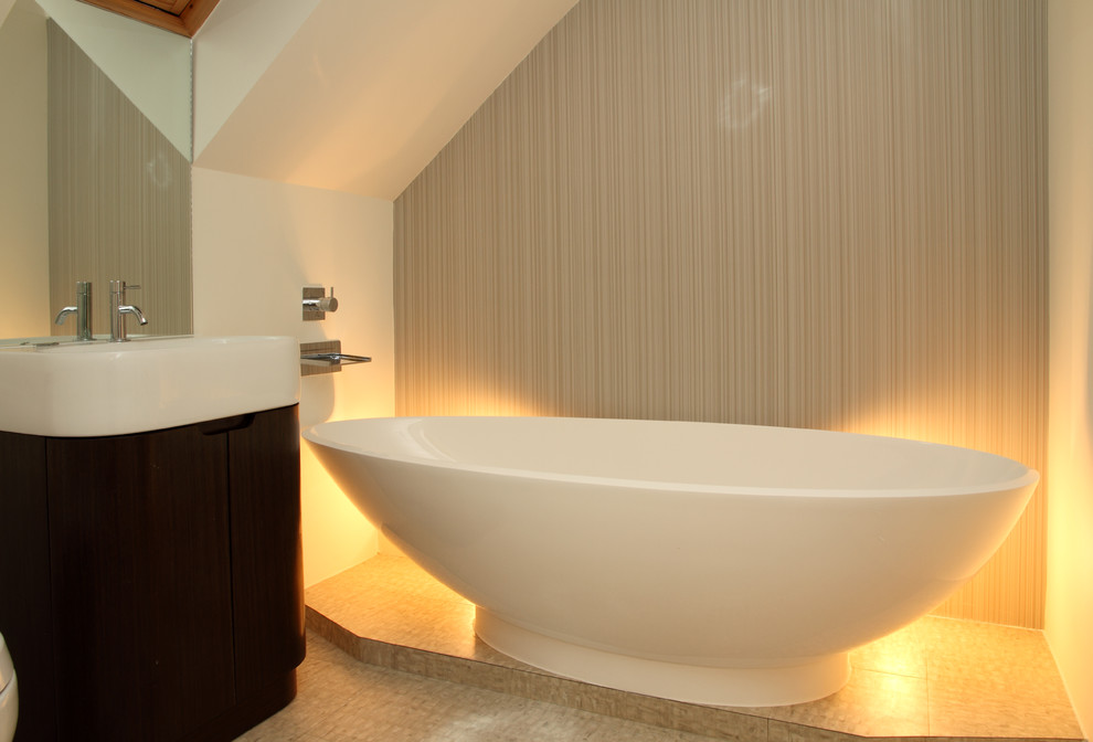 Kleines Modernes Badezimmer En Suite mit Waschtischkonsole, flächenbündigen Schrankfronten, dunklen Holzschränken, freistehender Badewanne, beiger Wandfarbe und Linoleum in London