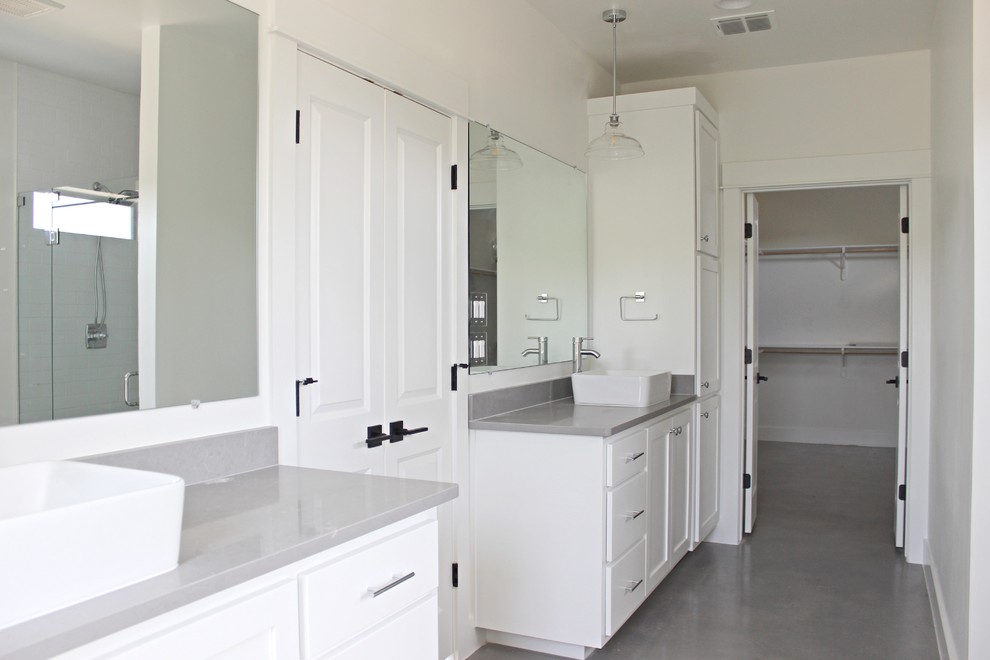 Inredning av ett lantligt grå grått en-suite badrum, med vita skåp, en dubbeldusch, vita väggar, betonggolv, ett fristående handfat, bänkskiva i kvartsit, grått golv och dusch med gångjärnsdörr