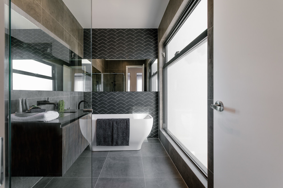 Стильный дизайн: ванная комната в современном стиле с плоскими фасадами, темными деревянными фасадами, отдельно стоящей ванной, черной плиткой, врезной раковиной, серым полом, открытым душем и черной столешницей - последний тренд