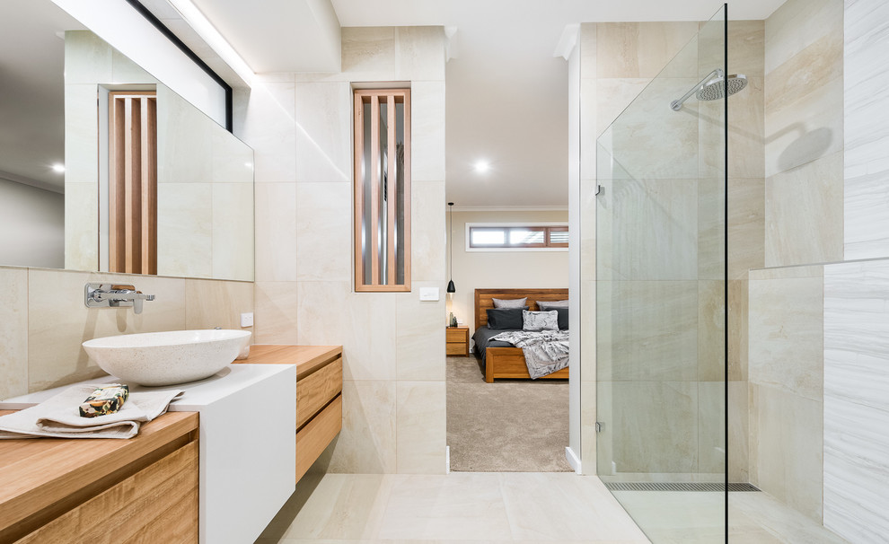 Свежая идея для дизайна: большая главная ванная комната в современном стиле с фасадами островного типа, светлыми деревянными фасадами, отдельно стоящей ванной, открытым душем, унитазом-моноблоком, бежевой плиткой, керамической плиткой, бежевыми стенами, полом из керамической плитки, настольной раковиной, столешницей из искусственного кварца, бежевым полом и открытым душем - отличное фото интерьера