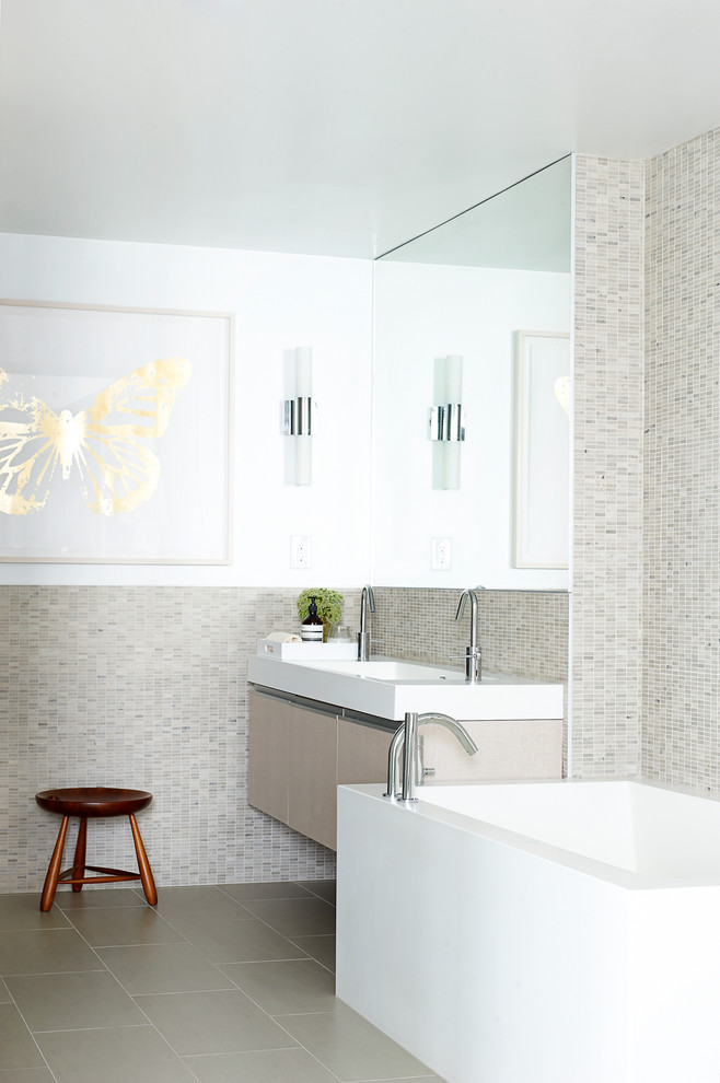 This is an example of a medium sized modern ensuite bathroom in Toronto with flat-panel cabinets, light wood cabinets, a freestanding bath, a one-piece toilet, beige tiles, mosaic tiles, white walls, porcelain flooring, an integrated sink and solid surface worktops.