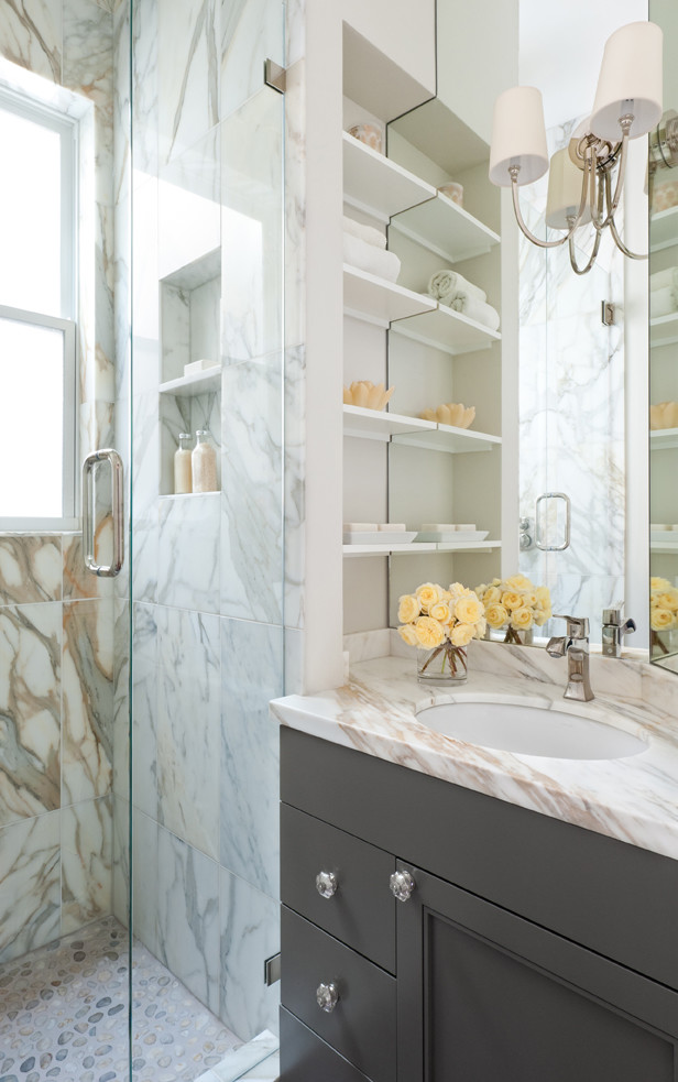 This is an example of a medium sized traditional bathroom in San Francisco with recessed-panel cabinets, grey cabinets, an alcove shower, beige tiles, grey tiles, white tiles, stone tiles, white walls, a submerged sink and marble worktops.