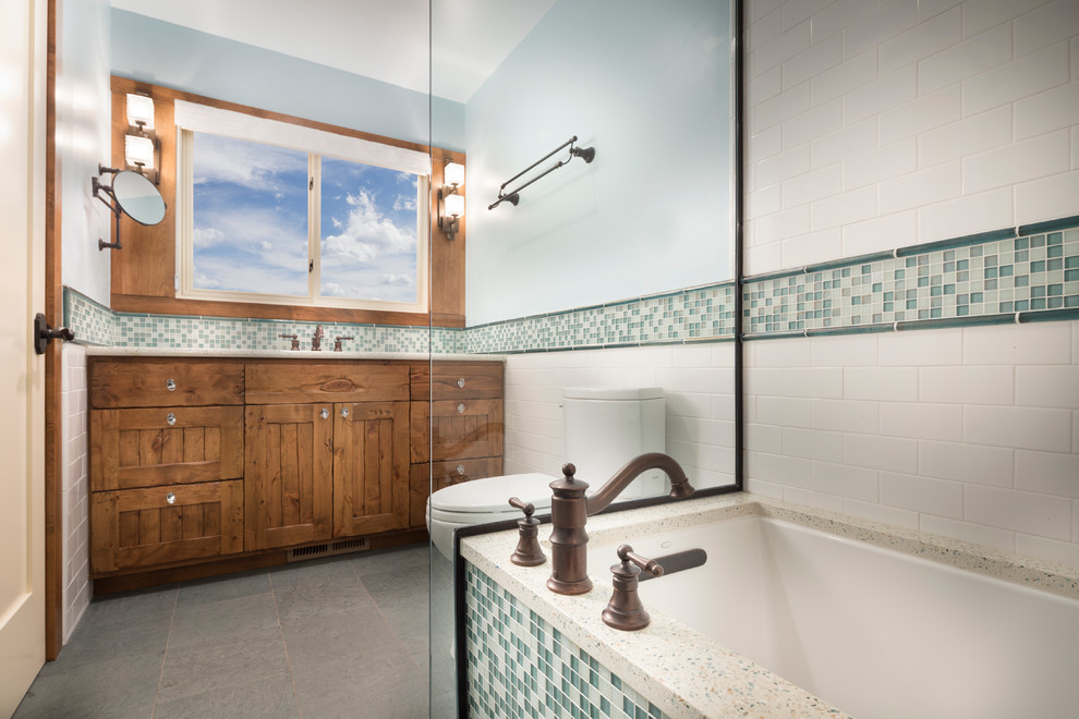 Exempel på ett mellanstort rustikt badrum, med ett nedsänkt handfat, ett platsbyggt badkar, grön kakel, glaskakel, en toalettstol med hel cisternkåpa, luckor med profilerade fronter, skåp i mellenmörkt trä, en dusch/badkar-kombination, blå väggar, skiffergolv och granitbänkskiva